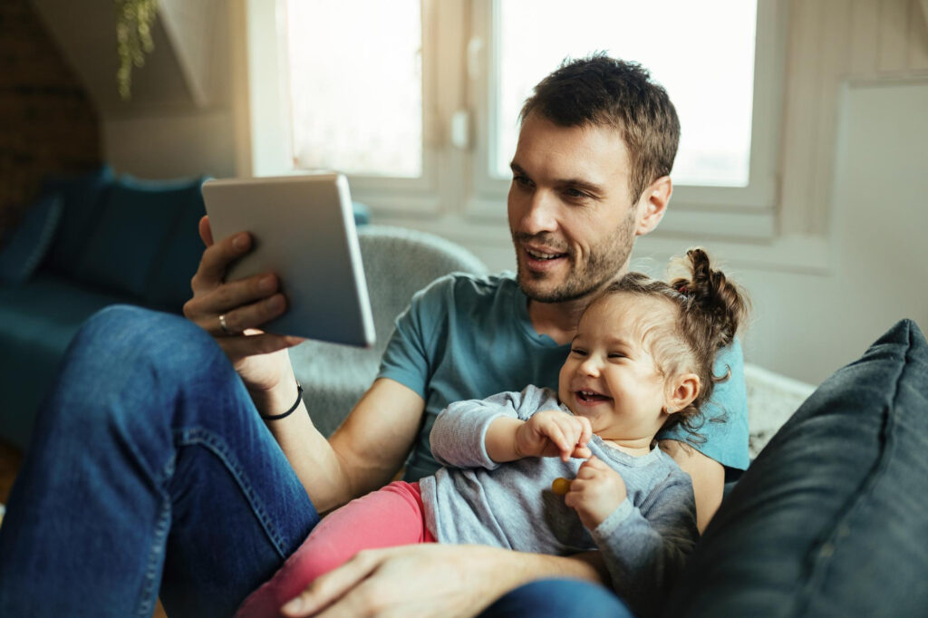 Pai com uma criança da Geração Alpha consumindo conteúdo no tablet.